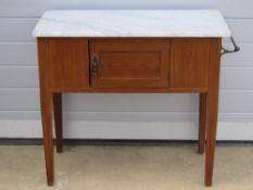 An Edwardian stained pine washstand with end towel rail and single cupboard door with white marble