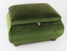 A vintage green velvet covered foot stool raised over wooden bun feet and opening reveal