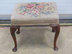 A needlepoint and mahogany footstool with shaped legs and shell motif to the knee, 53 x 41 x 46cm.
