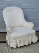 A Victorian low fireside chair upholstered in plain calicos fabric, raised over turned legs.