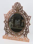 A fine and heavy pierced brass and copper easel mirror having oval bevelled edge glass,