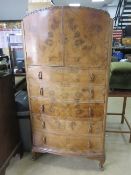 A c1930s chest of drawers having twin doors over five graduated drawers,