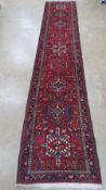 A red ground woollen rug having multi coloured geometric pattern upon,