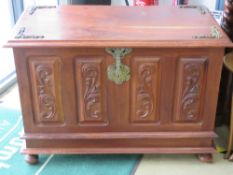 A 20thC carved panel lidded chest in Kingwood having cast brass ornamentation upon,