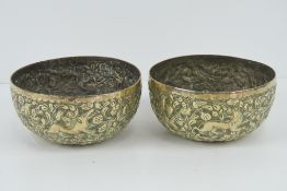 A pair of repoussé brass bowls having foliate decoration with birds and hunting dogs upon,
