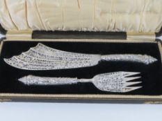 An ornate Victorian set of HM silver fish servers having pierced and repoussé fish themed pattern