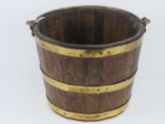A coopered oak bucket having brass banding and swing handle, 33.5cm diameter.