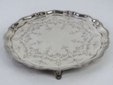 An HM silver salver raised over four scroll work feet having floral engraving upon and hallmarked