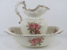 A wash jug and bowl, cream ground with pink rose pattern upon.