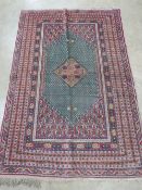 A green and pink ground woollen rug having geometric pattern upon,