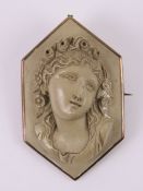 A carved lava stone cameo being a three dimensional female portrait with floral crown,