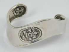 A silver bangle having carved floral dec