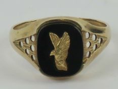 A 9ct gold and onyx signet ring having inset yellow metal eagle to onyx cabachon, hallmarked 375,