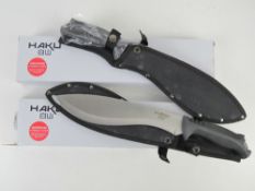 Two Anglo Arms Haku machetes having protective sheaths in original packaging.