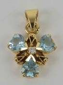 A blue topaz and diamond floral pendant having central round cut diamond with three heart shaped