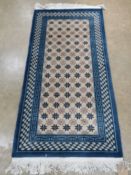 A Chinese woollen rug, blue and cream ground having label upon and measuring 172 x 78cm.