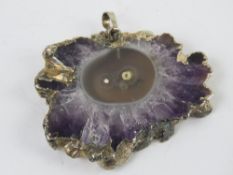 An amethyst geode slice mounted as a pendant, 5 x 3.8cm.