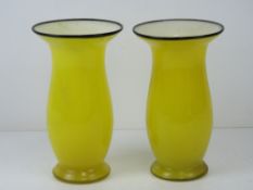 A pair of overlaid glass vases having yellow ground with white interior and black rim,