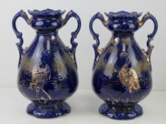 A pair of blue ground vases having gilded heron design upon, each standing 27cm high.