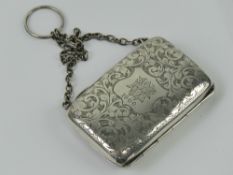 A white metal coin purse on chain having floral engraving throughout and central monogram shield