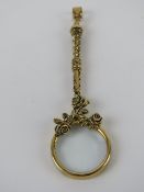 A 925 silver magnifying glass pendant having floral decoration and gilded, measuring 8.3cm inc bale.
