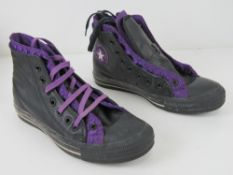 A pair of black leather Converse All Star trainers with two pairs of laces in black and purple,