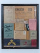 A framed montage of WWII items inc rations books, identity card, driving licence, arm bands,