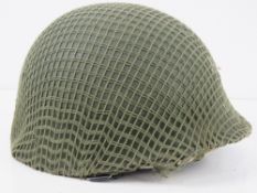 A US helmet having hard liner, leather liner, chin strap and camo netting upon.