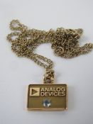 A 14k gold square shaped pendant marked 'Analog Devices' and having white stone under, stamped 14k,