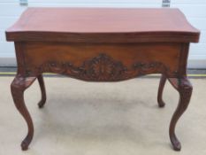 A 20th century mahogany gaming table raised over par-carved and shaped legs with acanthus leaf and