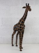 A fine floor standing African sculpture of a giraffe, leather covered with painted spots,