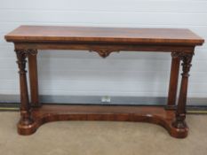 A rosewood buffet serving table raised over carved pillars united by an inverted solid base,