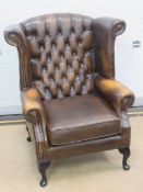 A brown leather wing back armchair,