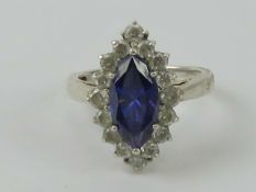 A silver cocktail ring having central marquise cut blue/purple stone surrounded by round cut white