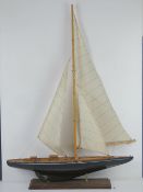 A model of a sail boat on stand, having fabric sails, un-named, 61cm in length.