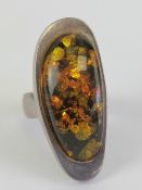 A Baltic amber cocktail ring, the large oval cabachon set in white metal approx 4cm in length,