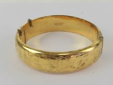 A vintage English made rolled gold hinged bangle having floral engraving to front, 6cm internal dia,