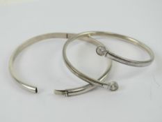 A silver bangle having white stone terminals, stamped 925.