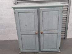 A painted pine cupboard having twin doors opening to reveal straight cut shelves within, 3ft 10''