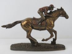 A contemporary bronzed effect sculpture of a race horse with jockey upon, approx 29.5cm in length,
