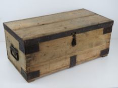 A vintage pine lidded trunk having iron bracing and end handles, measuring 62 x 31 x 26cm.