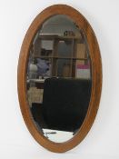 An Edwardian oval bevelled edge wall mirror, mahogany frame strung with boxwood and ebony in a