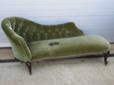 An Edwardian button back chaise lounge raised over shaped and scrolled legs.