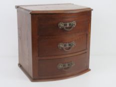 A mahogany table top barrel fronted chest of three jewellery drawers, pediment deficient.