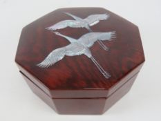 A high lacquer Oriental jewellery box of octagonal form having inset mother of pearl cranes or