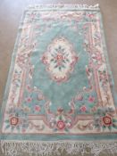 A green ground woollen rug having pink and cream floral pattern measuring 196 x 120cm.