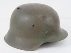 A WWII German M42 helmet having two holes caused by single bullet, original liner (a/f).
