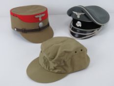 Three reproduction WWII German caps inc SA Kepi, SS peaked cap and another.
