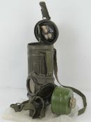 A WWII German gasmask having filter and tin with straps.