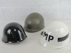 Three helmets including; black painted helmet, white painted IMP helmet and another.